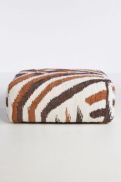 an orange, brown and white striped bag on a white surface with a black stripe across the bottom