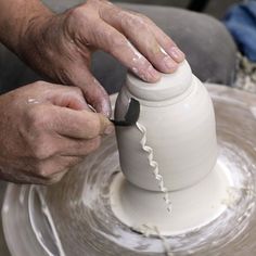 a person making a vase out of clay on a potter's wheel with one hand