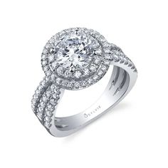 a white gold engagement ring with diamonds on the band and an oval center stone surrounded by round