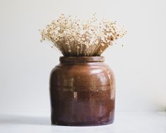 a vase with dried flowers in it sitting on a table