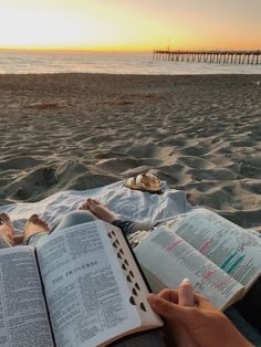 a person laying on the beach reading a book