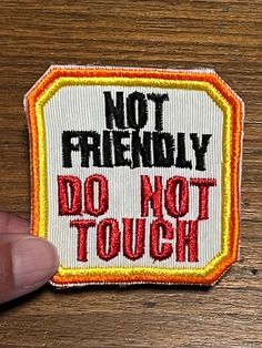 a hand holding a patch with the words not friendly do not touch it on it