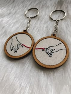 two wooden hoops with embroidered images of hands holding each other's hand on them