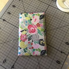 a piece of fabric with flowers on it sitting on a cutting board next to scissors