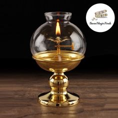 a candle is lit in a glass bowl on top of a wooden table with a black background