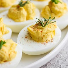 deviled eggs are topped with herbs and seasoning on a white platter, ready to be eaten