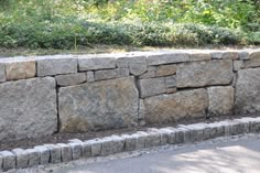 a large stone wall sitting next to a road