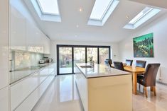 an open kitchen and dining room with skylights above the countertop, along with glass doors leading outside