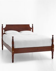 a wooden bed frame with white sheets and pillows on the headboard, against a white background