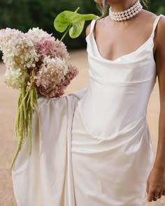 a woman in a white dress holding a bouquet of flowers