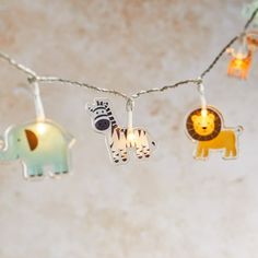 some lights that have animals on them hanging from a line with one light turned on