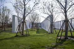 several trees are in the grass next to some white walls and windows on each side