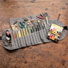 a pencil case filled with art supplies on top of a wooden table