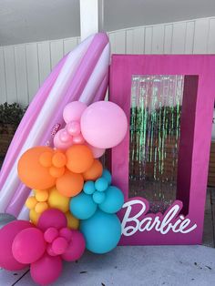 there is a bunch of balloons on the ground next to a pink frame and sign