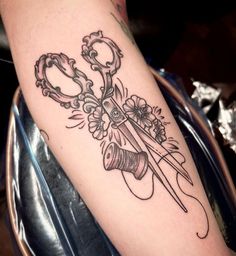 a tattoo with scissors and flowers on it