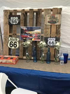 a table topped with vases filled with flowers next to wooden pallets and signs