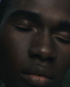 a close up of a person with gold eyeshadow and necklace on their neck