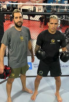 two men standing next to each other with boxing gloves on their hands and one holding a punching mitt