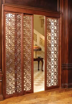 an open wooden door with intricate carvings on the doors and side panels, leading to a foyer