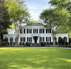 a large white house sitting on top of a lush green field