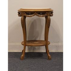 an antique wooden table with carvings on the top and bottom, against a white wall