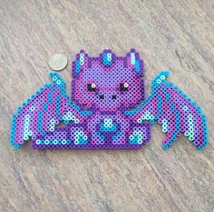 a purple and blue beaded object sitting on top of a table next to a penny