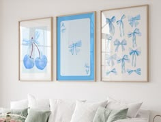 three framed pictures hang on the wall above a couch in a living room with white furniture