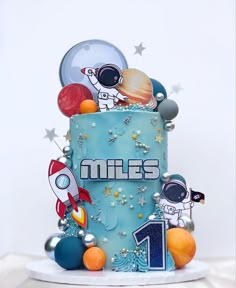 a blue cake decorated with space related items and the number one on it's side