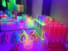 some glasses and other items are sitting on a table in front of a mirror that is lit up with colored lights