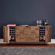 a wooden cabinet with wine bottles and glasses on it in front of a gray wall