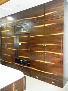 a bed sitting in a bedroom next to a wooden cabinet filled with drawers and cupboards