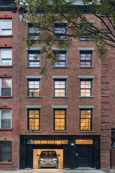 a car parked in front of a tall brick building with lots of windows and doors