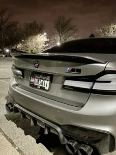 the back end of a silver bmw car parked in a parking lot at night time