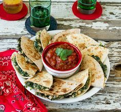 some tortillas and salsa are sitting on a wooden table with other food items