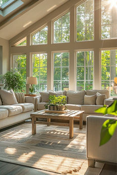 a living room filled with lots of furniture under a large window next to a wooden coffee table