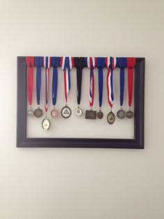 a group of medals hanging on a wall next to a black framed frame with a red, white and blue ribbon