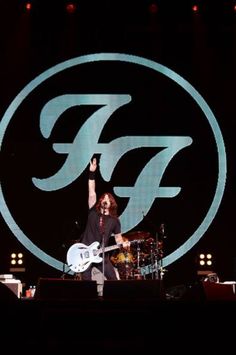 a man on stage with his hand up in the air while playing an electric guitar