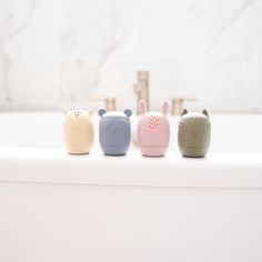 four little animals are lined up in a row on the edge of a bathtub