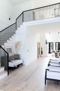 a living room with white walls and wooden flooring next to a set of stairs