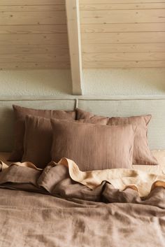 an unmade bed with brown linens and pillows