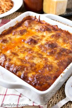 a casserole dish with cheese and sauce in it sitting on a table next to other dishes