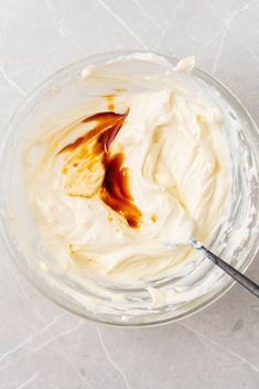 a glass bowl filled with whipped cream on top of a white counter next to a spoon