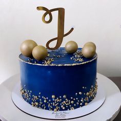 a blue and gold birthday cake with the letter j on top