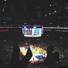 people are watching a basketball game on the big screen in an arena at night time