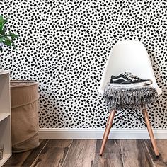 a white chair sitting in front of a wall with black and white designs on it