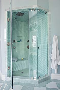 a bathroom with a walk in shower next to a white toilet and bathrobe