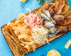 an assortment of different types of food on a platter with lemons and rosemary