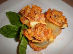 some food is on a white plate with green leafy leaves and google plates pasta