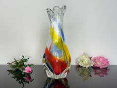 a glass vase sitting on top of a table next to flowers