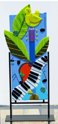 an artistic sculpture made out of paper with musical instruments and plants on it's sides